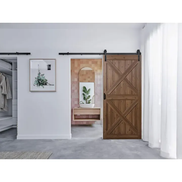 LADON Ovi Saluuna liukuovi asennettuna – X‑kuvioitu tummanruskea ovi avoinna olohuoneen ja eteisen välissä